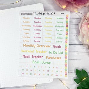 Pode incluir: Uma folha de autocolantes de planeamento coloridos com o texto "Thumbelina Print" e "TP156". Os autocolantes incluem dias da semana, visão geral mensal, metas, rastreador de treino, lista de tarefas, rastreador de hábitos, compras e brainstorming. Os autocolantes estão em fundo branco.