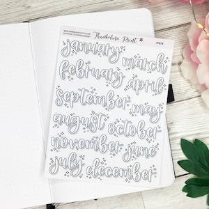 Op de afbeelding: Een vel wit stickerpapier met zwarte contouren van de maanden van het jaar in een cursief schrift. Het stickervel is gelabeld met "Thumbelina Print*" en "TP879".