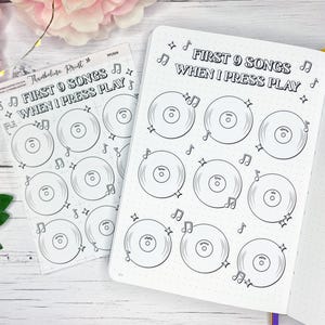 May include: A sticker sheet and a journal page with the text "FIRST 9 SONGS WHEN I PRESS PLAY". The design features vinyl records, musical notes, and stars. The journal page is open, showing a dotted grid.