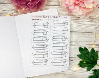 May include: A sheet of printable planner stickers featuring 10 illustrations of stacked books. The stickers are black and white and have a simple, minimalist design. The text "2 Stacked Books" is at the top of the sheet.