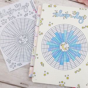 May include: A white page with a blue and light blue sleep log chart with a crescent moon and stars. The chart is divided into sections with a grid pattern. The page is decorated with yellow stars.