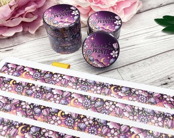 May include: Five rolls of purple and gold washi tape with a floral and moon design. The tape has the text "Thumbnail Print" on it.