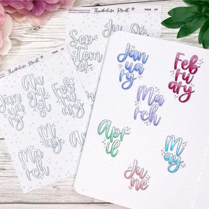May include: Two sheets of stickers with handwritten month names. One sheet has the months in gray, the other sheet has the months in various colors. The months are January, February, March, April, May, June, July, August, September, October, November, and December.