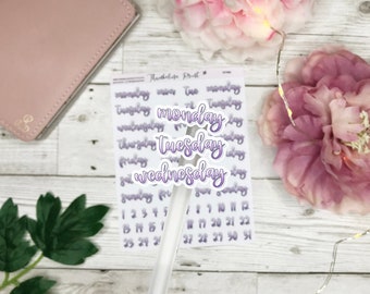 May include: A sheet of planner stickers with the days of the week in a purple script font. The days "Monday", "Tuesday", and "Wednesday" are highlighted. Also included are number stickers for the days of the month.