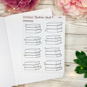 May include: A sheet of printable planner stickers featuring 8 different designs of stacked books with a sparkling effect. The text "3 Stacked Books" is at the top of the sheet.