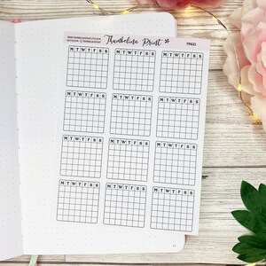 Puede incluir: Una hoja de pegatinas de planificador imprimibles con 12 cuadr&iacute;culas semanales en blanco etiquetadas con los d&iacute;as de la semana: lunes, martes, mi&eacute;rcoles, jueves, viernes, s&aacute;bado, domingo. Las pegatinas est&aacute;n impresas en papel blanco y tienen un borde negro.