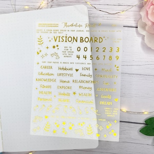 Könnte beinhalten: Transparente Bögen mit goldenen Folienaufklebern für ein Vision Board, mit Text wie "Vision Board", Zahlen und Wörtern wie "Karriere", "Hobbys" und "Liebe".