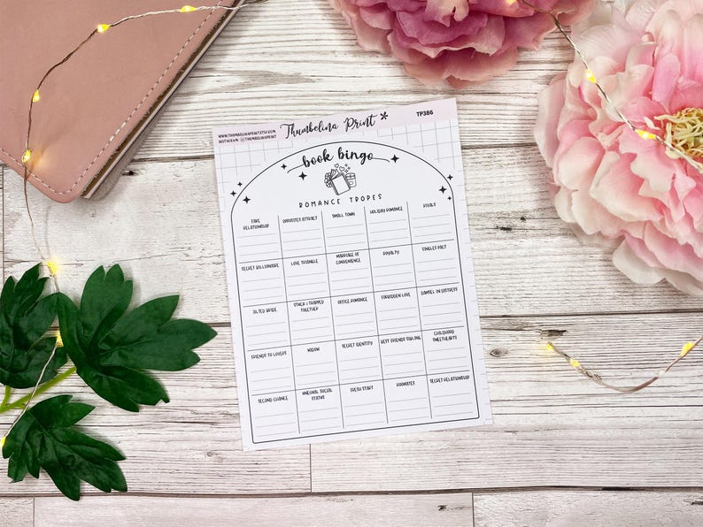 May include: A printable book bingo card with a black and white design. The card features a list of common romance tropes, such as "fake engagement" and "enemies to lovers".