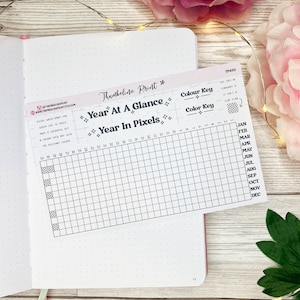 May include: A black and white printable planner page with the title "Year at a Glance" and "Year in Pixels". The page is divided into a grid with 12 columns representing months and 52 rows representing weeks. There are two colour key sections labelled "Colour Key" at the top of the page.