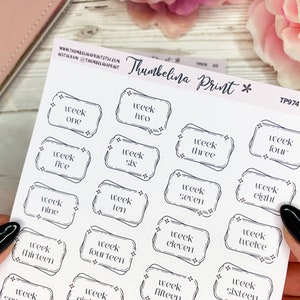 May include: A sheet of white sticker paper with black outlined stickers that say "week one" through "week sixteen". The stickers are in a decorative frame with stars.