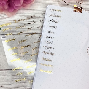Små månads transparenta klistermärken i guld | Dekorativ och funktionell planering | Journalklistermärken | Genomskinliga klistermärken | Månadsrubriker | Manus
