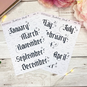 May include: Two sheets of white sticker paper with black gothic font month names. The sheets are printed with a repeating pattern of clouds and stars. The first sheet has the months January, March, November, September, and December. The second sheet has the months May, July, February, and April.
