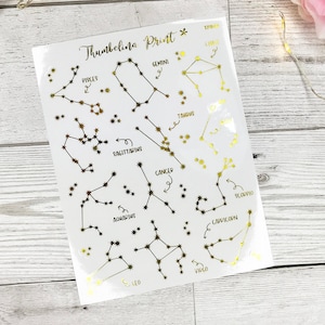 May include: A sheet of gold foil constellation stickers with the names of each constellation written in black ink. The constellations include Pisces, Gemini, Taurus, Sagittarius, Cancer, Scorpio, Capricorn, Aquarius, Leo, and Virgo.