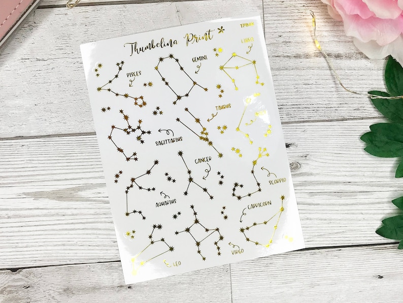 May include: A sheet of gold foil constellation stickers with the names of each constellation written in black ink. The constellations include Pisces, Gemini, Taurus, Sagittarius, Cancer, Scorpio, Capricorn, Aquarius, Leo, and Virgo.