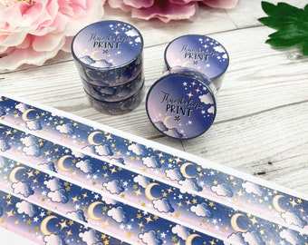 May include: A roll of washi tape with a blue and pink night sky pattern featuring clouds, stars, and a crescent moon. The tape is labeled "Thumbelina Print".