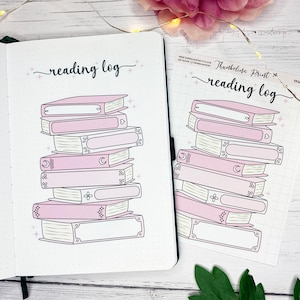 May include: A reading log notebook and a matching sticker featuring a stack of pink books. The notebook is open, displaying a dotted grid. The sticker has the same design. Both items have the words "reading log" in cursive.