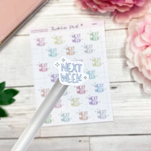 Könnte beinhalten: Ein Bogen Aufkleber mit dem Text "Next Week", der mehrmals in verschiedenen Farben wiederholt wird. Die Aufkleber befinden sich auf einer weißen Holzoberfläche.