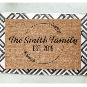 May include: A brown coir doormat with the text "The Smith Family EST. 2019" in a black circle with a leafy design.