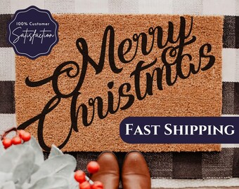 May include: A brown coir doormat with the text "Merry Christmas" in black cursive lettering. The text "FAST SHIPPING" is printed in white on a blue banner at the bottom of the mat.