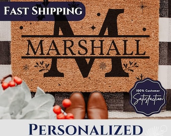 May include: Personalized doormat with the name "MARSHALL" and the letter "M" in a split monogram style. The doormat is brown and has a wintery design with snowflakes and holly.