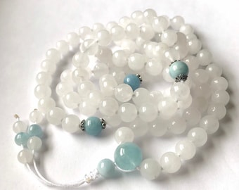 May include: White and blue gemstone mala prayer beads with a tassel. The mala is made of white stones with blue accents.