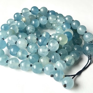 May include: A strand of light blue gemstone beads with a dark blue cord. The beads are round and have a smooth, polished finish.