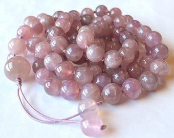 May include: A strand of pink gemstone beads with a knotted tassel. The beads are round and have a translucent appearance.