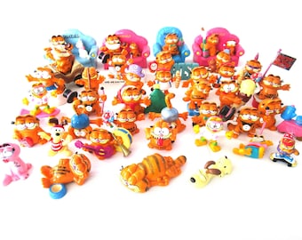 May include: A collection of over 30 colorful plastic figurines of Garfield the cat in various poses and settings. The figurines are all orange and feature Garfield's signature grin. Some figurines include accessories like a surfboard, a guitar, and a Christmas tree.