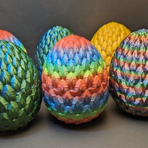 May include: Five dragon egg-shaped ornaments with a textured, scaly surface. The ornaments are painted in various colors, including green, blue, red, yellow, and purple.