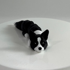 Peut inclure: Une figurine d'un chien en 3D imprimée en noir et blanc, couchée sur le côté. Le chien a une poitrine blanche et un nez noir.