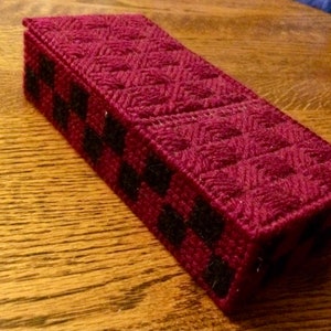 May include: A burgundy and black woven box with a geometric pattern. The box is made of yarn and has a rectangular shape.