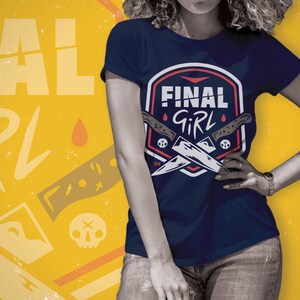 K&ouml;nnte beinhalten: Ein marineblaues T-Shirt mit einem wei&szlig;en und roten Grafikdesign mit zwei gekreuzten Messern und dem Text "FINAL GIRL".