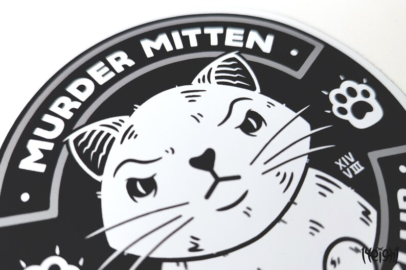 Pu&ograve; includere: Adesivo rotondo in bianco e nero con un'illustrazione di un gatto e il testo "MURDER MITTEN." Il gatto ha un'espressione maliziosa e guarda direttamente lo spettatore. L'adesivo ha un bordo grigio.