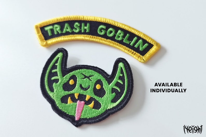 Pu&ograve; includere: Due toppe ricamate, una con una creatura verde simile a un goblin con una lingua rosa e l'altra con uno stendardo giallo che recita "Trash Goblin".