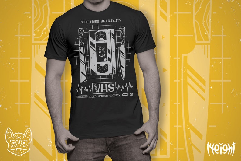 May include: Black t-shirt with a graphic of a VHS tape and knives. The text "GOOD TIMES BAD QUALITY" and "VHS VIDEO HORROR SOCIETY" is printed on the shirt.