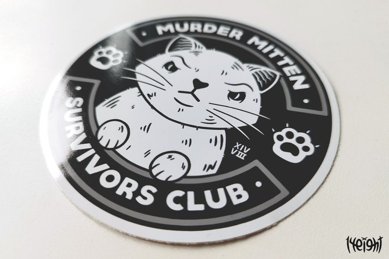 Pu&ograve; includere: Adesivo bianco e nero con un gatto dei cartoni animati con un'impronta di zampa e il testo "Murder Mitten Survivors Club".
