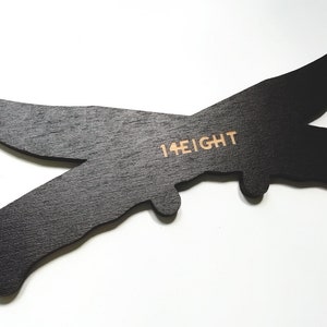 May include: Black wooden cutout of a plane with the text "14 EIGHT" printed on it.