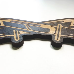May include: A wooden cutout of a plane in a dark brown color with a light brown outline.