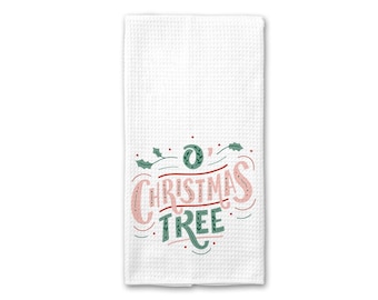 Peut inclure: Serviette de cuisine blanche avec un motif vert et rose qui dit "O' Christmas Tree".
