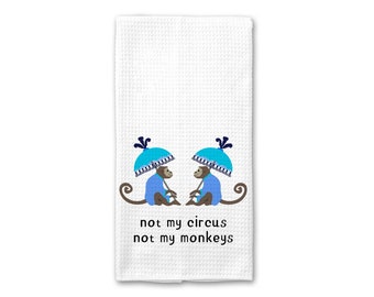 Könnte beinhalten: Weißes Küchentuch mit zwei Affen, die blaue Jacken tragen und blaue Regenschirme halten. Der Text "not my circus not my monkeys" ist unter den Affen gedruckt.