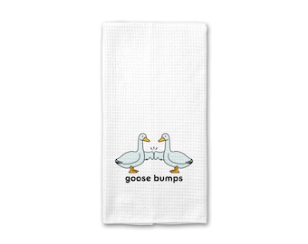 Könnte beinhalten: Weißes Küchentuch mit zwei Cartoon-Gänsen, die sich gegenüberstehen, und dem darunter gedruckten Text "goose bumps".