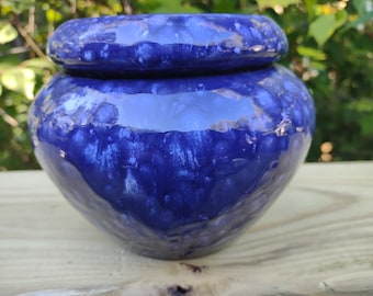 May include: A blue ceramic planter with a white speckled glaze. The planter has a wide mouth and a rounded body.
