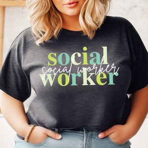 Può includere: Una maglietta grigio scuro con il testo "social worker" in lettere maiuscole colorate. Le lettere sono in tonalità di verde, blu e giallo.