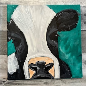 May include: A close-up painting of a cow's face. The cow has black and white markings and a light brown nose. The background is a solid teal green.