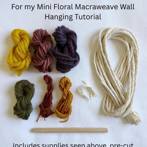 May include: A craft supply kit for a mini floral macraweave wall hanging, featuring text that reads Supply Kit For my Mini Floral Macraweave Wall Hanging Tutorial. Includes six small yarn bundles in mustard, maroon, purple, olive, rust, and gold, a length of cream cord, and a wooden dowel.