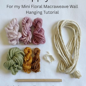 May include: A craft supply kit for a mini floral macraweave wall hanging, featuring text that reads Supply Kit For my Mini Floral Macraweave Wall Hanging Tutorial. Includes various colored yarn skeins, a long beige cord, and a wooden dowel.