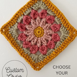May include: A crocheted square with a flower design in shades of pink, yellow, and green. The text "Custom Order" and "Choose Your Colors!" is visible below the square.
