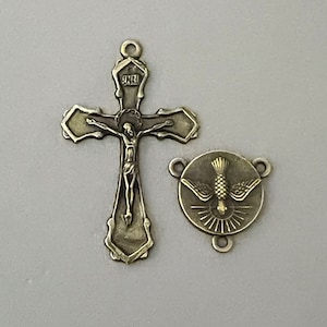 May include: A silver-toned metal crucifix with a figure of Jesus Christ on the cross. The crucifix is attached to a silver-toned metal dove charm with a gold-toned center.