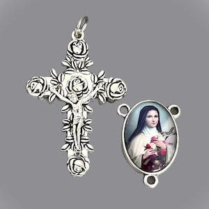 May include: Silver rosary with a crucifix featuring a silver Jesus figure and a silver oval medal with a colorful image of Saint Thérèse of Lisieux.