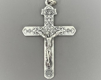 May include: Silver crucifix pendant with an ornate design and the inscription "INRI" on the top.